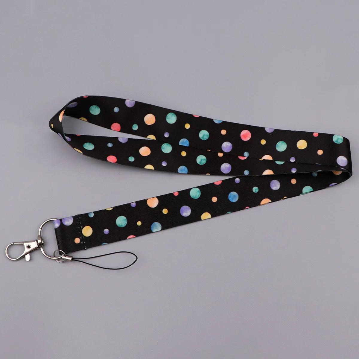 Black fabric lanyard with multi-colored polka dots, featuring a heart shape and attached to a key ring.