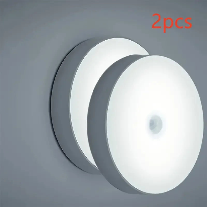 Two round motion sensor LED night light discs shown against a gray background.
