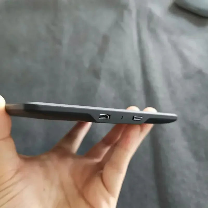 A hand holds a black Kindle Paperwhite e-reader displaying its side profile.
