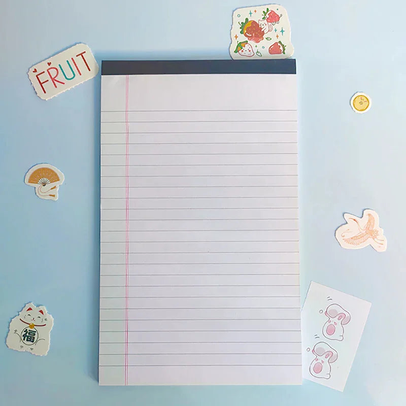 A white lined writing pad is shown with a fruit sticker and a small yellow coin nearby.