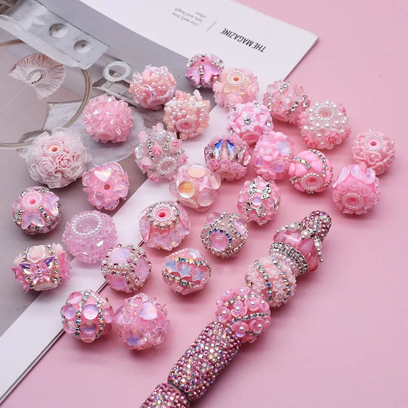 Pink and iridescent acrylic flower beads arranged on a white card for jewelry making