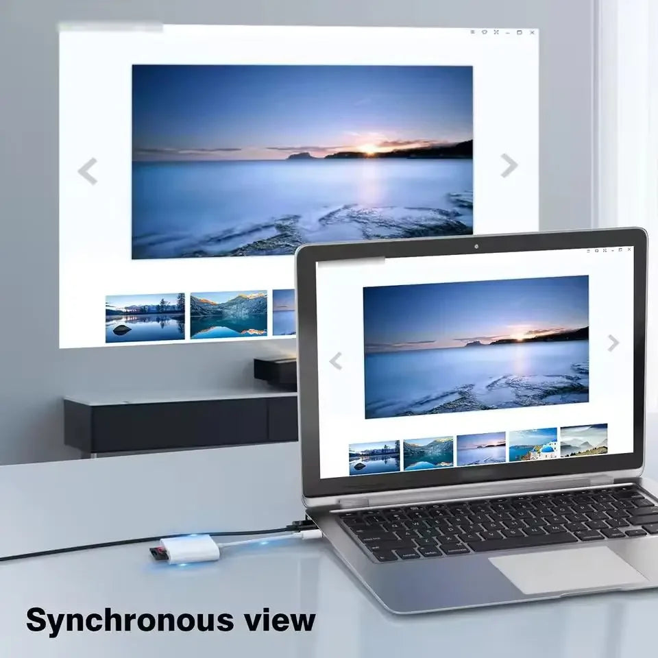 A laptop displays a synchronized view of a scenic sunset landscape on a screen, next to a larger monitor.