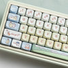 A close-up view of light-colored mechanical keyboard keycaps featuring cute animal designs like rabbits and cats.