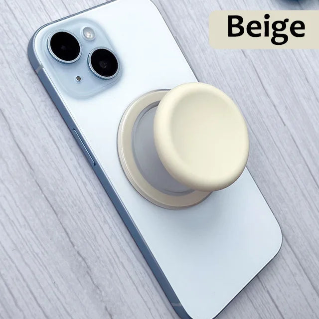 A beige 360 degree magnetic phone grip stand with a silicone cover placed on a white smartphone.