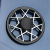 A black metal fidget spinner with a geometric design is shown against a light blue background.