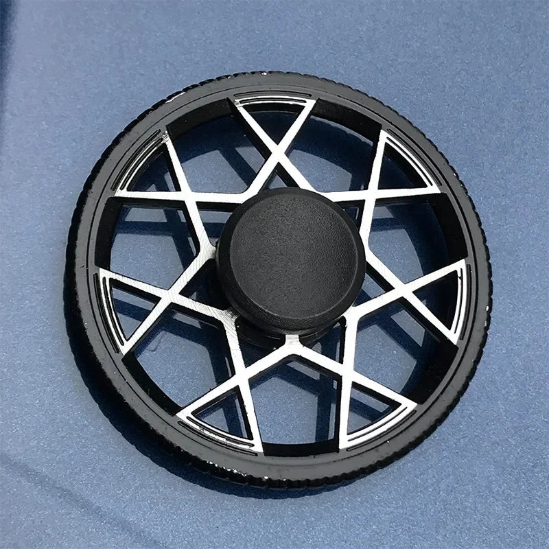 A black metal fidget spinner with a geometric design is shown against a light blue background.