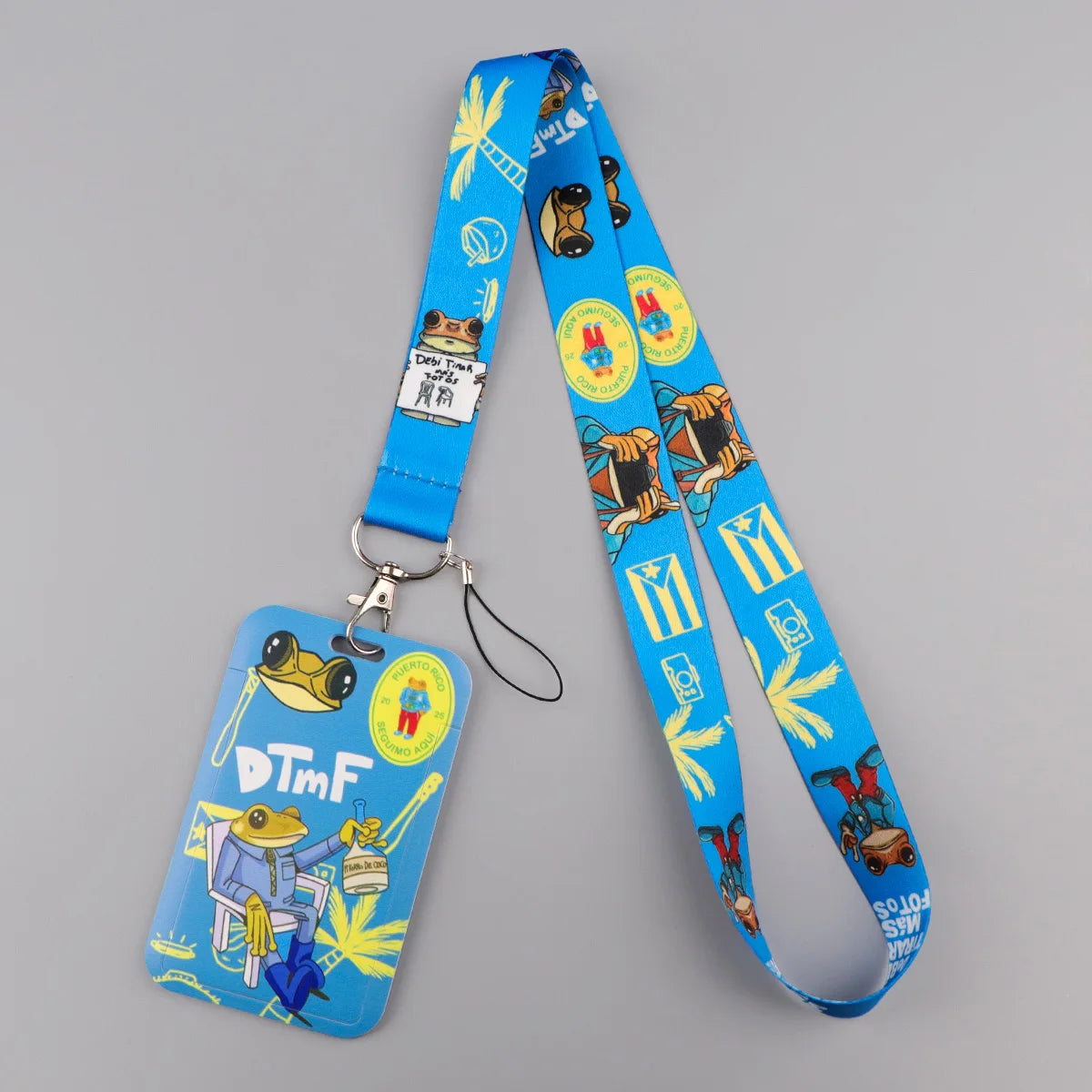 A blue lanyard with a card holder featuring various cat designs and tropical leaf patterns.