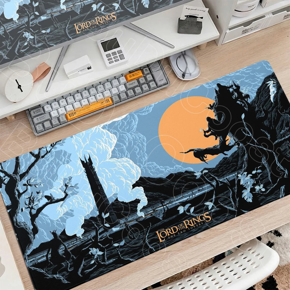A large blue and black Lord of the Rings themed gaming mouse pad placed on a wooden desk with accessories.