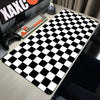 A black and white checkered desk mat is placed on a wooden desk next to a keyboard and mouse.