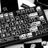 A close-up view of a black and white comic-style PBT keycap set featuring various function keys and modifiers.