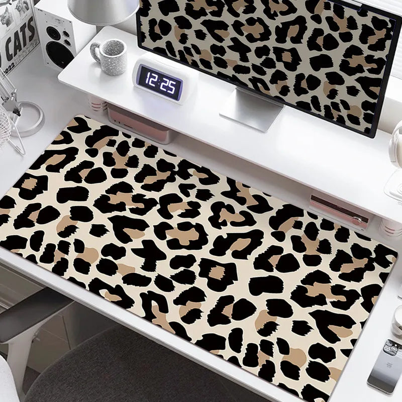 A large leopard print desk pad featuring black and tan spots, displayed on a white desk with a digital clock.