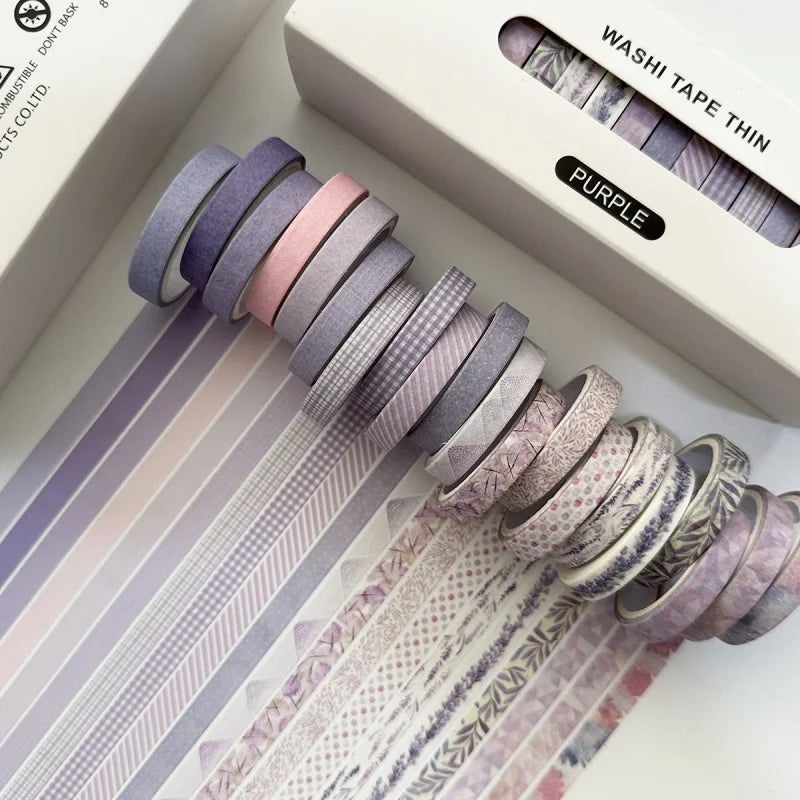 A stack of purple and pink washi tape rolls is displayed next to its packaging.