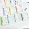 A collection of clear double-button binders in various colors and sizes for stickers and journaling.