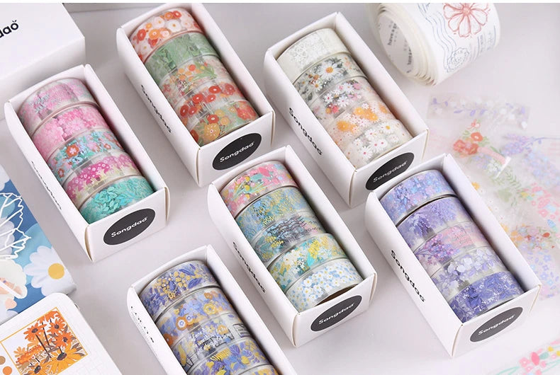 A collection of decorative transparent washi tape rolls in various colors and patterns displayed in individual boxes.