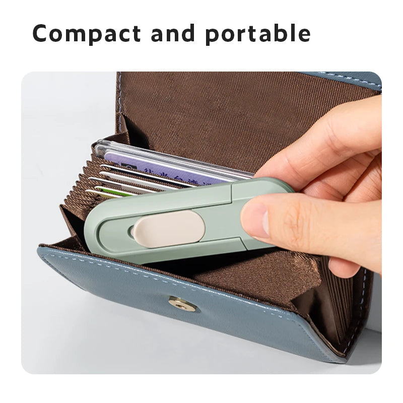 A hand is opening a brown leather-like case to reveal a small, light green paper cutter tool.
