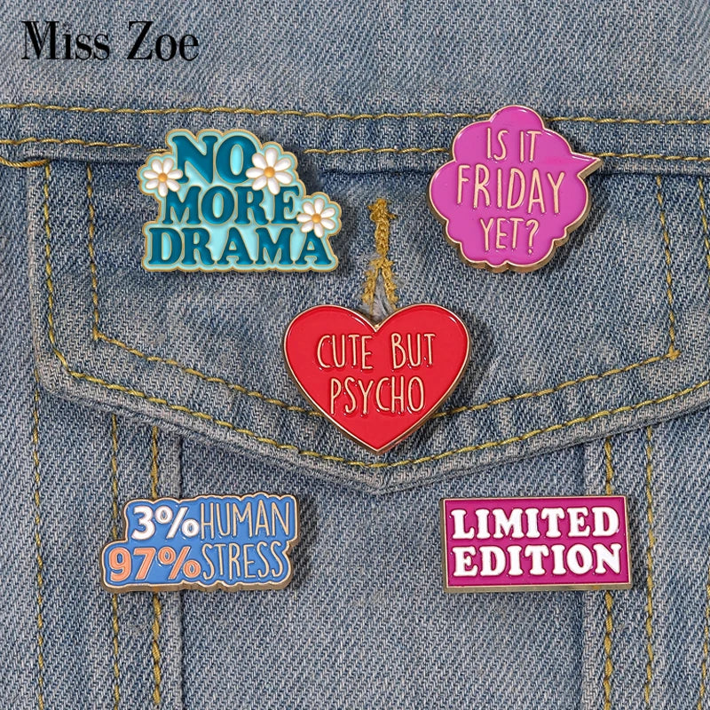 A set of enamel pins featuring sarcastic phrases like NO MORE DRAMA and CUTE BUT PSYCHO pinned onto a denim jacket.