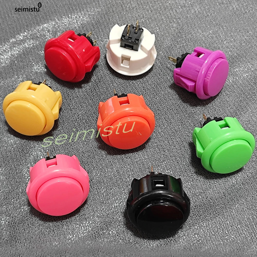 A collection of various colored arcade push buttons and micro switches displayed on a gray surface.