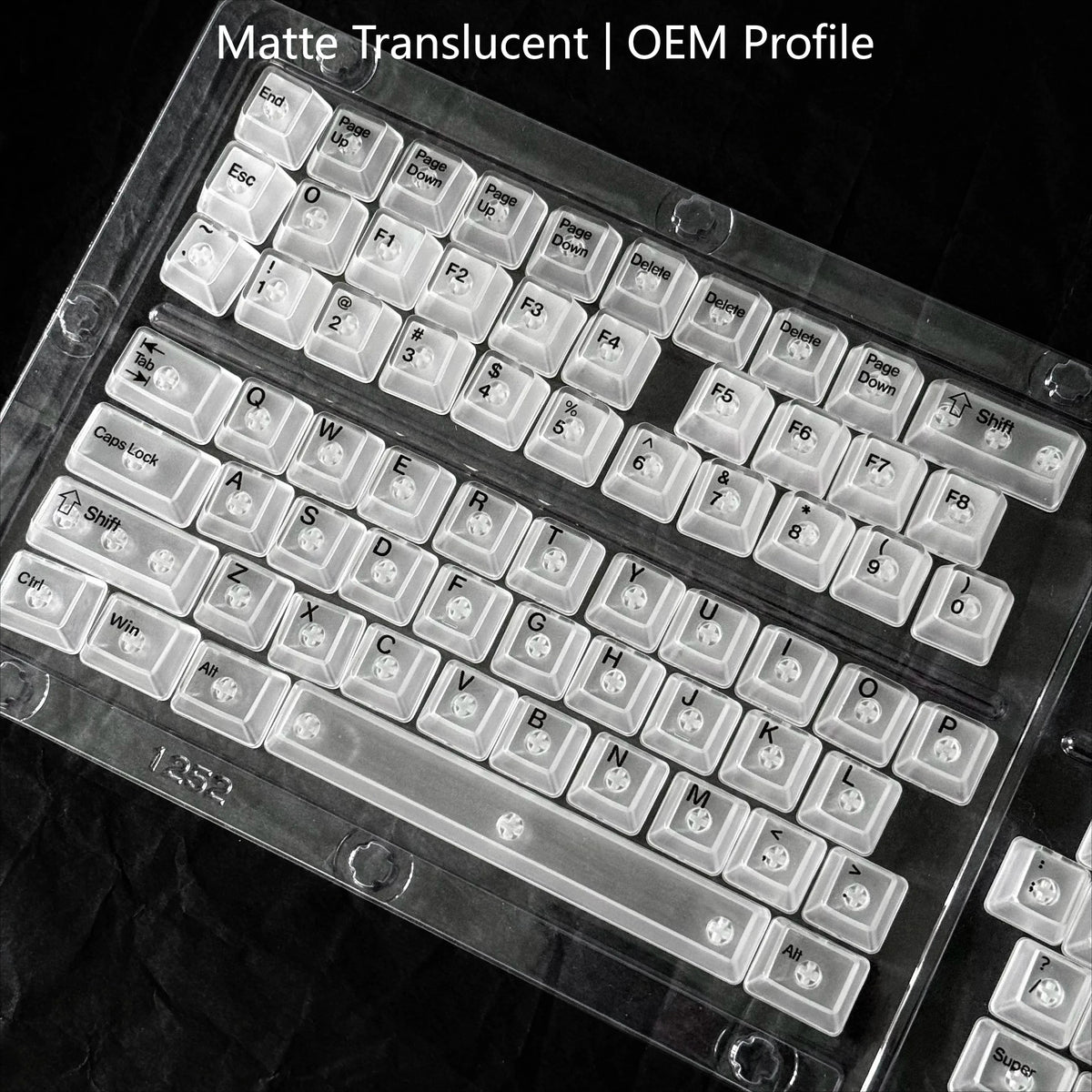 Nahaufnahme einer matten, durchscheinenden OEM-Profil-Tastatur mit weißen Tastenkappen auf einer dunklen Oberfläche.