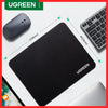 A black non-slip rubber mouse pad and a wireless mouse are shown on a white desk surface.