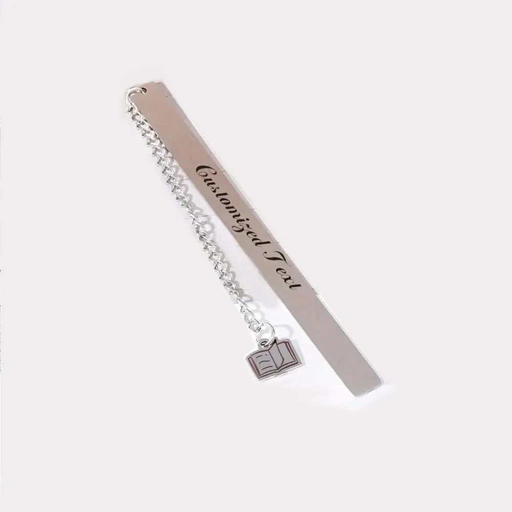 A silver stainless steel bookmark with engraved text hanging from a chain.