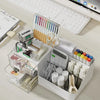 A white desk organizer with clear storage drawers holds various pens, pencils, and office supplies.