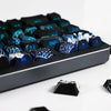 A close-up view of a black mechanical keyboard featuring blue side-lit PBT keycaps.