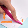 A hand is pressing down on a pink portable magnetic staple remover tool to remove staples from paper.