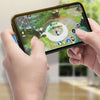 A hand holds a smartphone displaying a mobile game interface, with a braided USB charging cable visible.