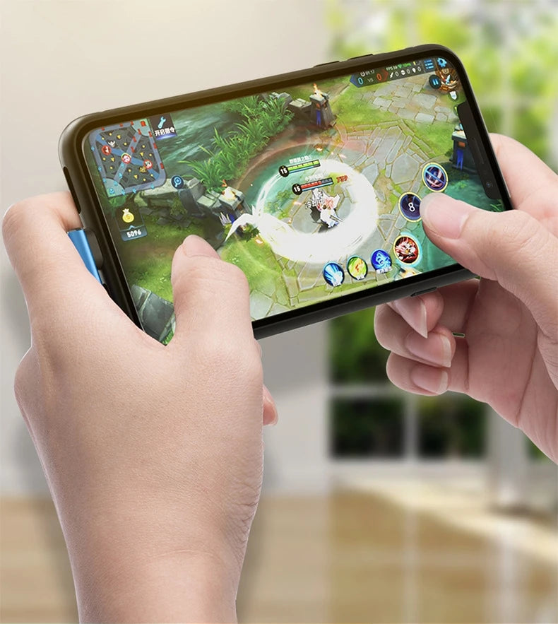 A hand holds a smartphone displaying a mobile game interface, with a braided USB charging cable visible.