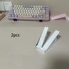 Two pink ergonomic keyboard riser stands with anti-slip bases are displayed on a light surface.