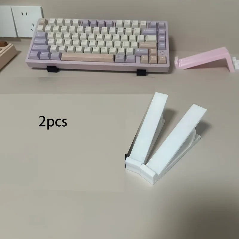 Two pink ergonomic keyboard riser stands with anti-slip bases are displayed on a light surface.