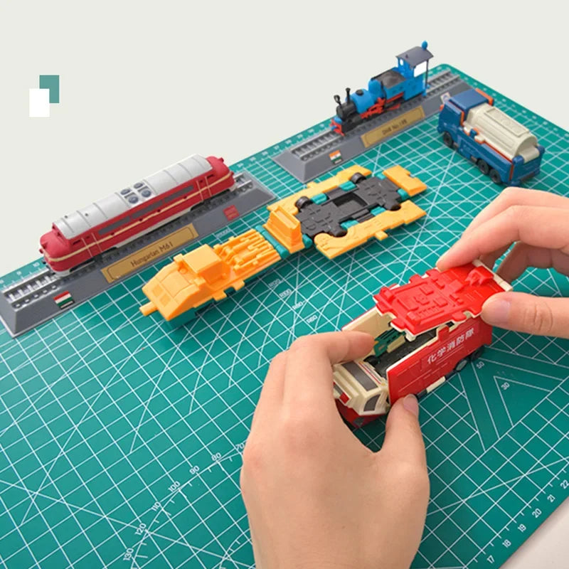A hand places a red and black component onto a green cutting mat with grid guides, showing a model kit assembly.
