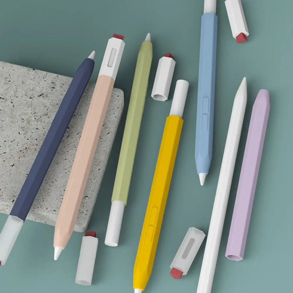 A collection of various colored silicone stylus pen protective covers arranged on a light green surface.