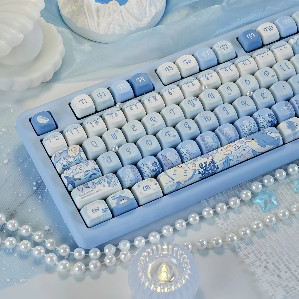 Blue sea themed PBT keycaps for a mechanical keyboard displayed on a light blue cloth.