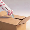 A white retractable cat paw utility knife is shown cutting open a cardboard box.