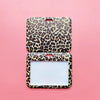 A square ID holder with a leopard print design set against a pink background.