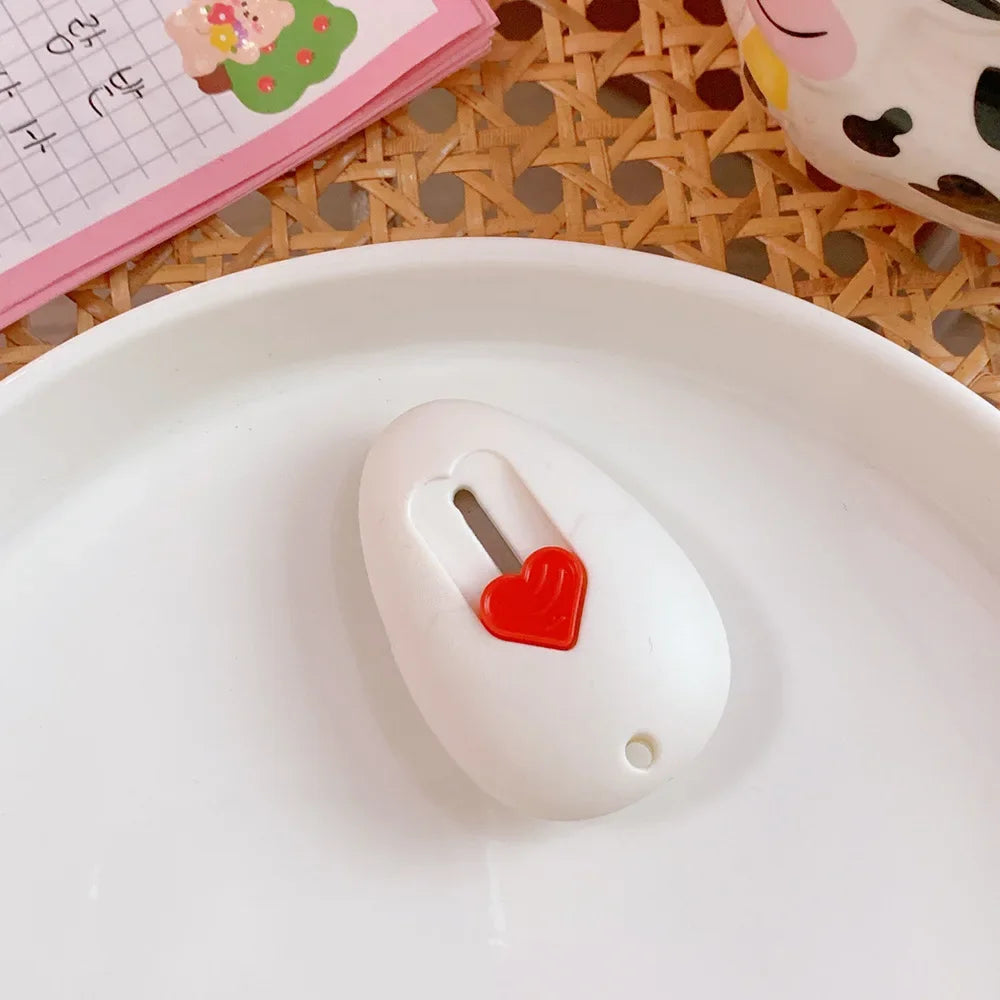 A white mini cat paw shaped cutter with a red heart detail resting on a white plate.