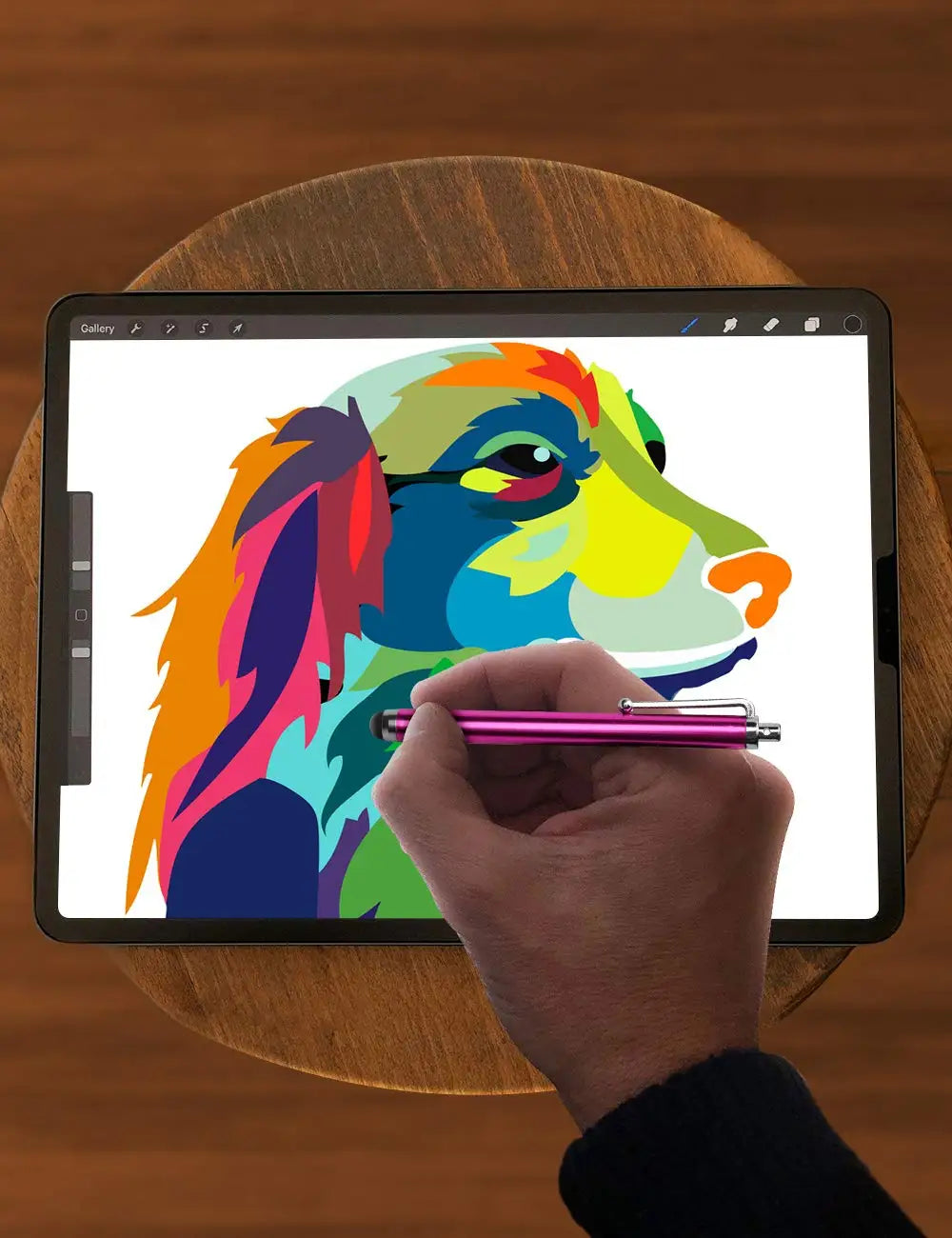 A hand holds a purple stylus pen drawing a colorful dog illustration on a digital tablet.