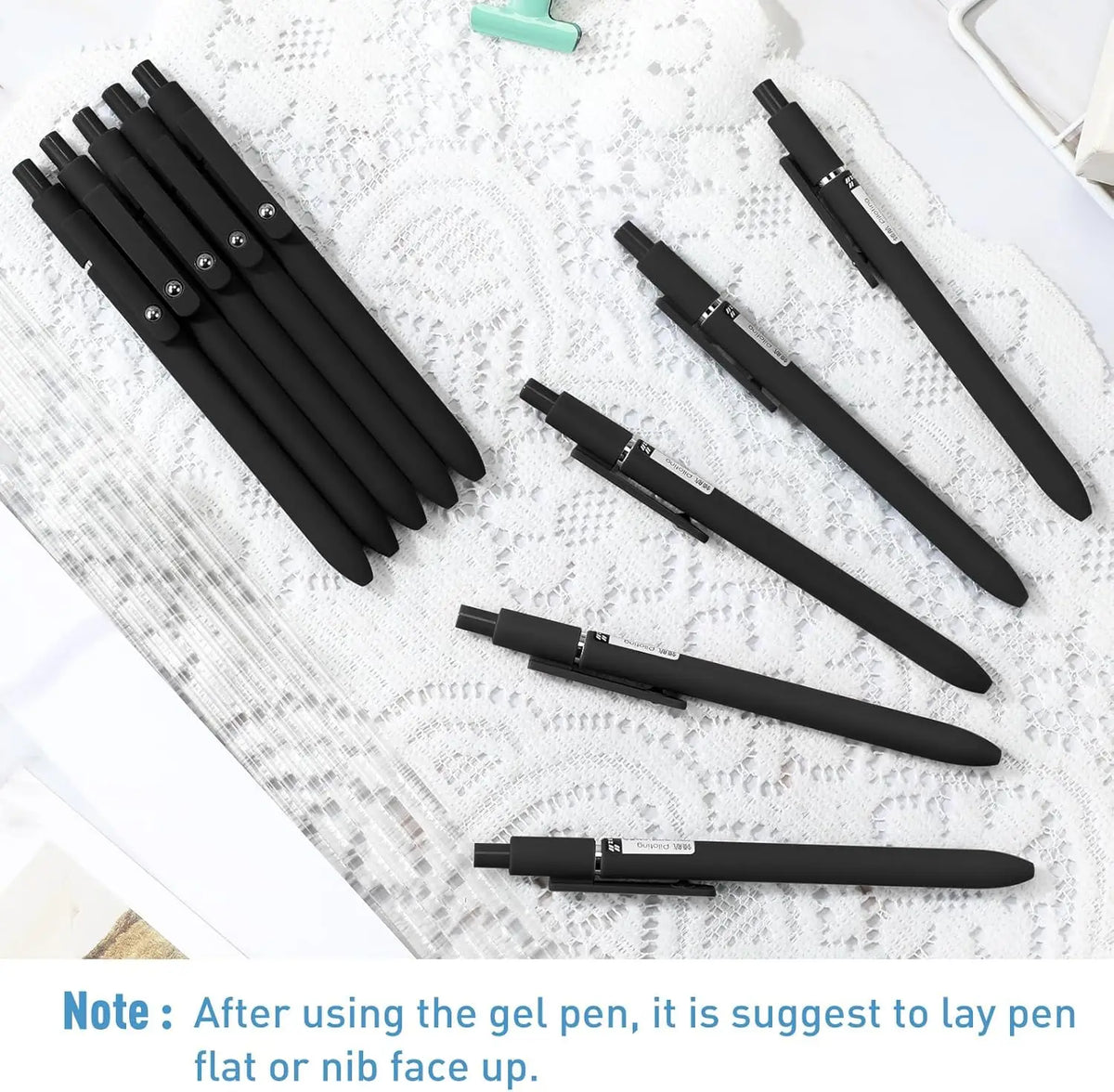 A set of ten black gel pens laid out on a white textured surface.