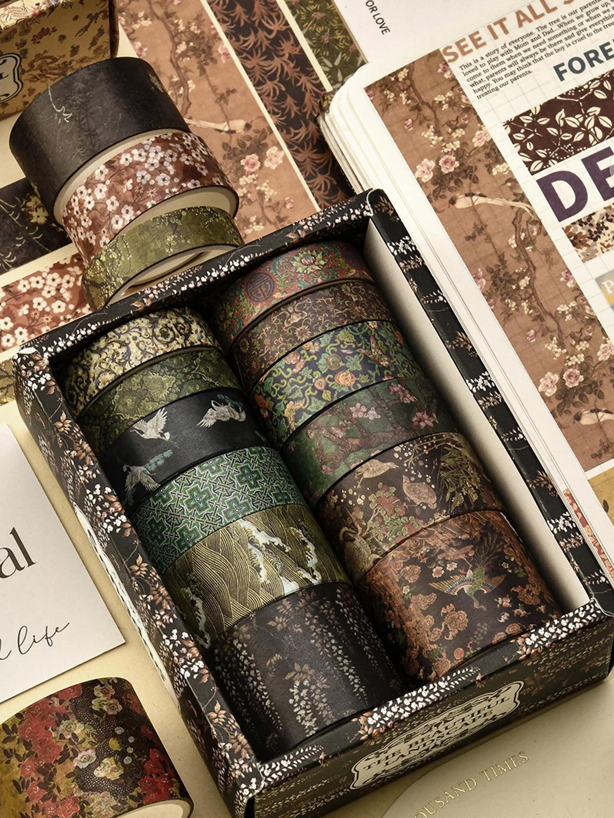 A box of vintage floral washi tape rolls in various shades of green, brown, and gold.