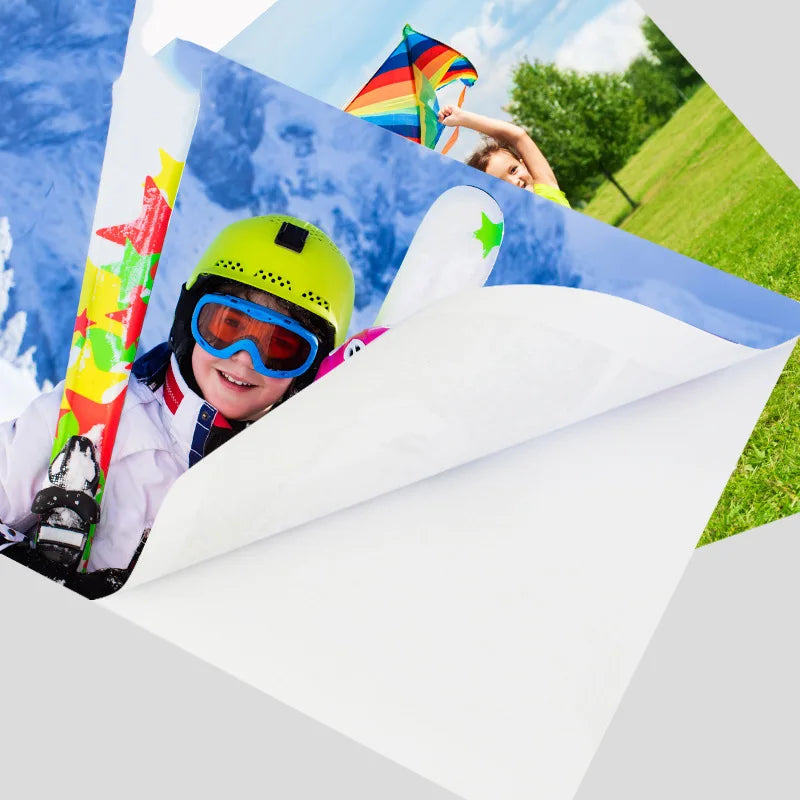 A child wearing a yellow helmet and goggles is holding a colorful kite against a blue sky in a grassy outdoor setting.