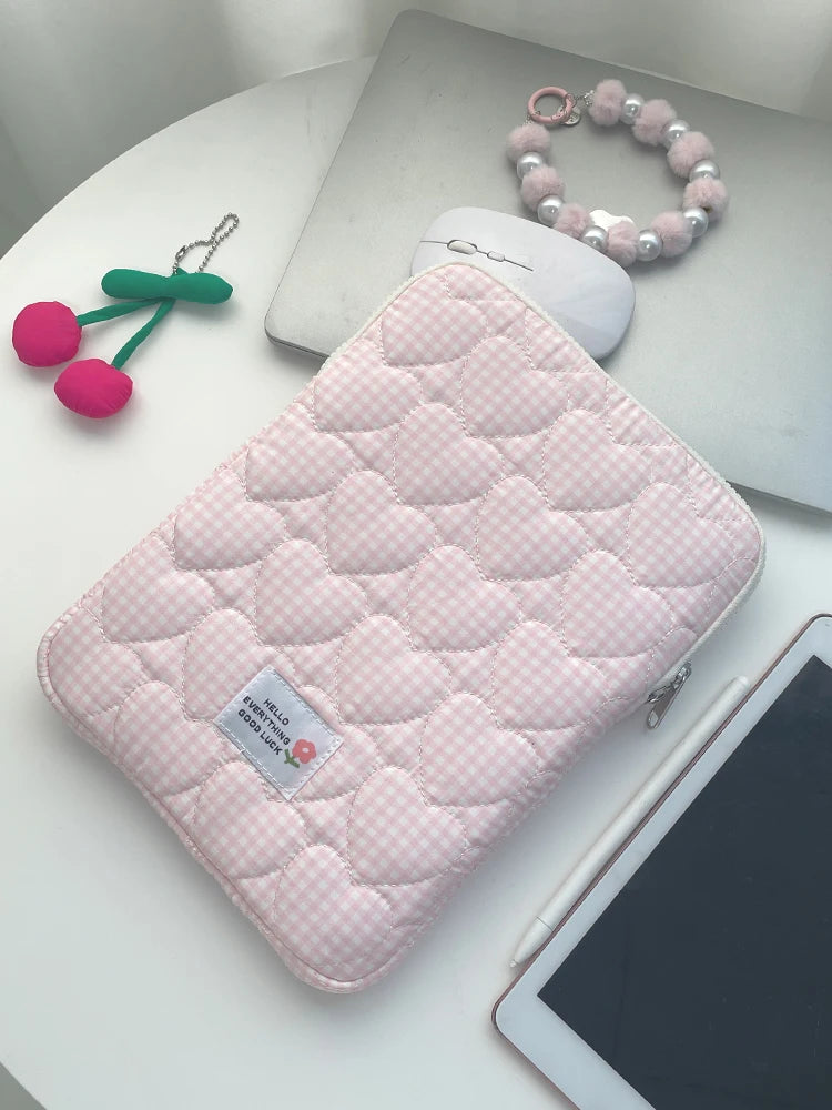 Pink quilted laptop sleeve with a matching pink beaded bracelet and green charm