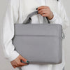 A person is holding a gray premium laptop sleeve for notebooks.