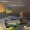 A mobile phone holder is displayed next to a panda-themed LED desk lamp on a white surface.