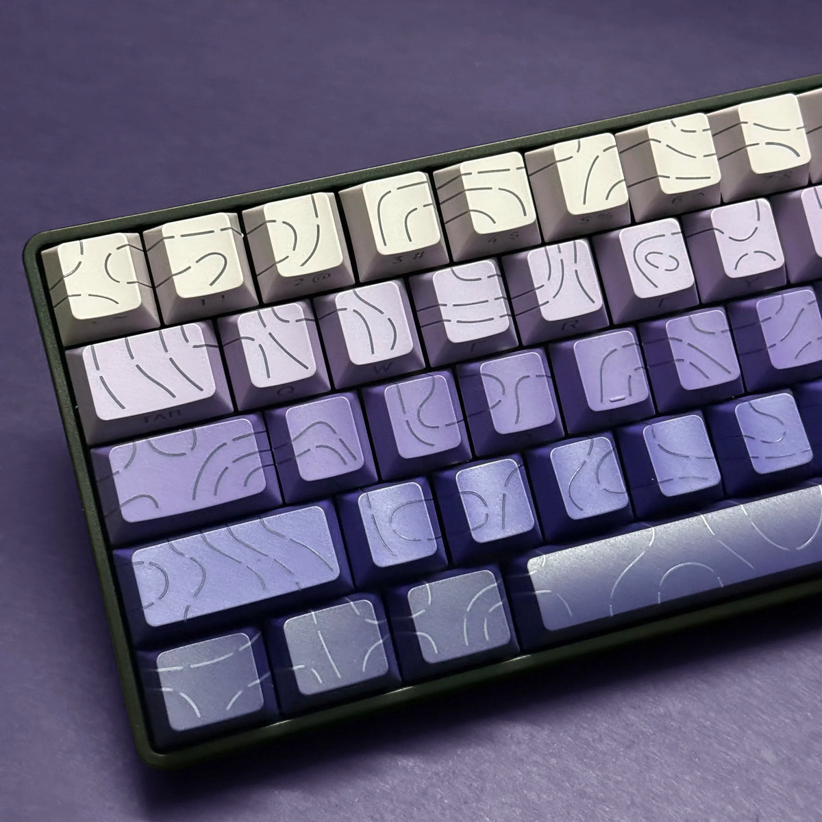 Vista cercana de un teclado mecánico con teclas gradientes en tonos morados y grises.