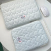 A light blue quilted laptop sleeve with a matching white wireless mouse is displayed on a white table.