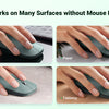 A dark gray ultra-slim wireless Bluetooth mouse is shown being used on various surfaces including a mouse pad, paper, cloth, 
