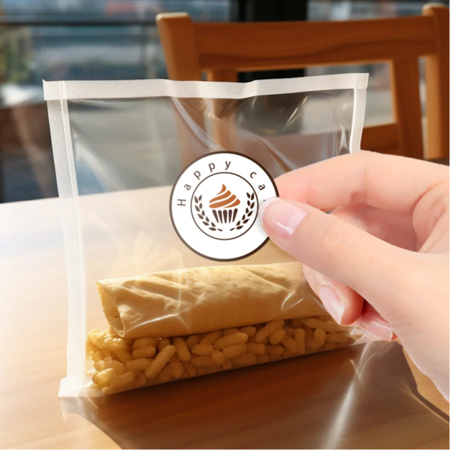 A hand is holding a clear plastic bag containing rolled yellow food items and a circular sticker labeled Happy Sale.