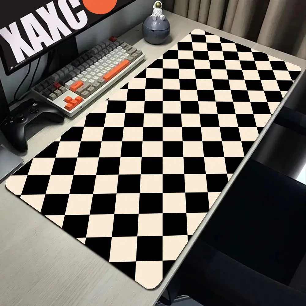 A black and white checkered desk mat is displayed on a desk next to a keyboard and gaming controller.