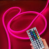 Una mano sostiene una tira de luz LED flexible multicolor, iluminando un fondo rosa vibrante.